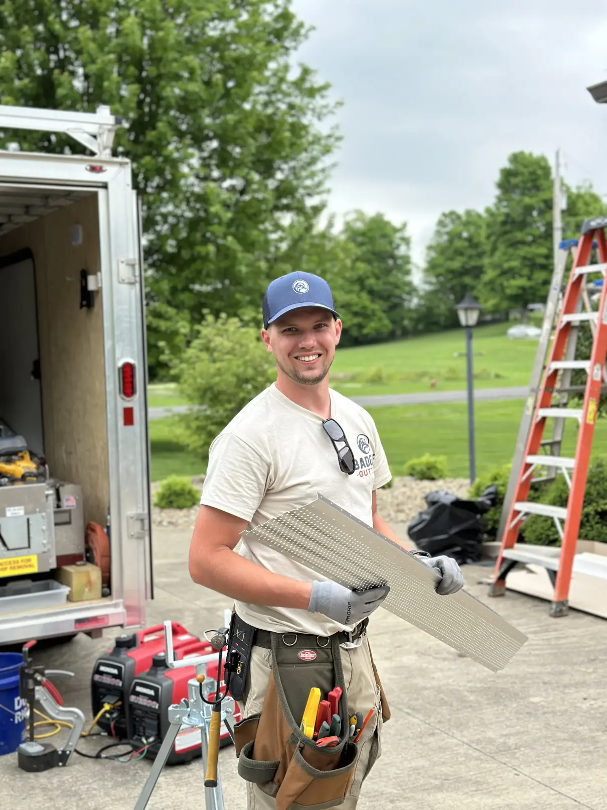 Badger Gutters technician carrying a perforated aluminum gutter guard panel from the trailer to the ladder