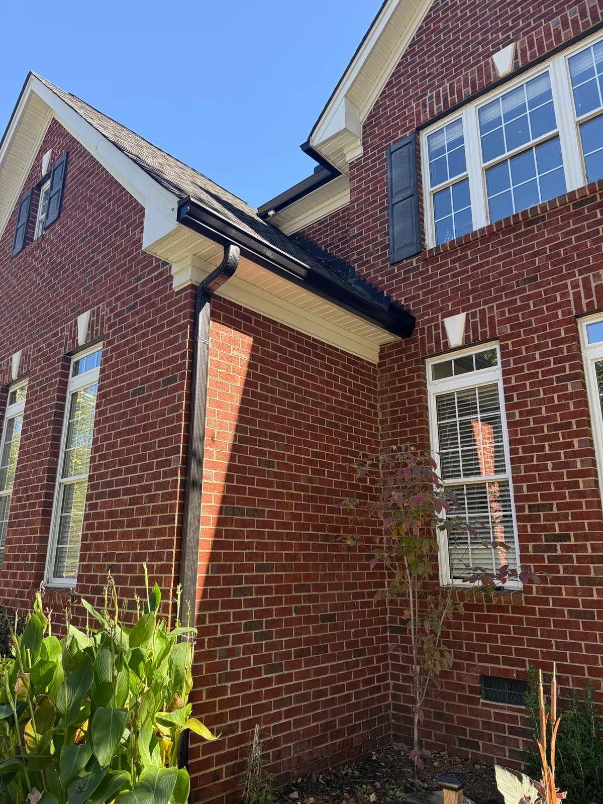 Red brick two-story with black seamless gutters, downspout and shutters in the Charlotte, NC area