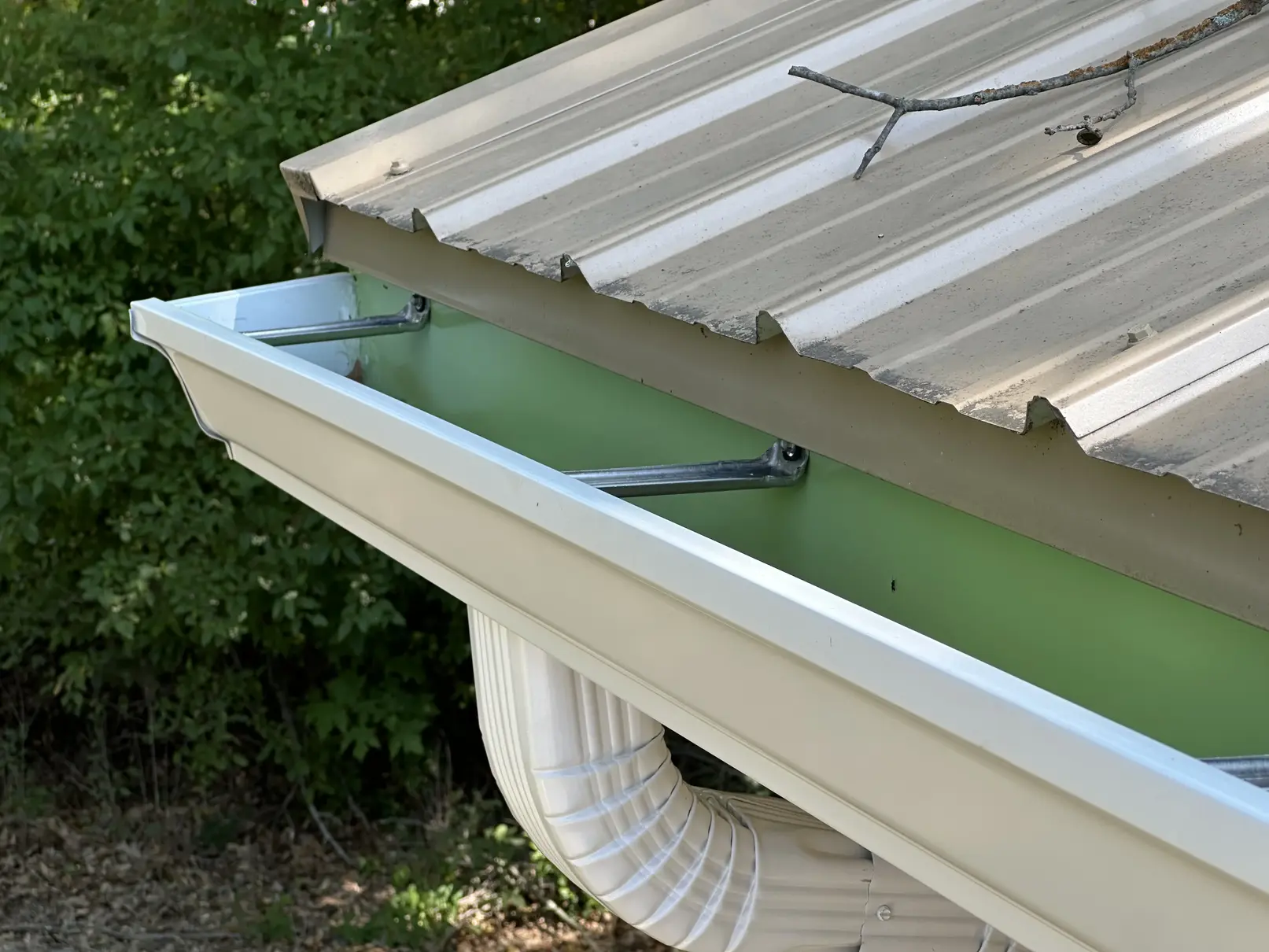 Close-up of heavy duty hidden hangers inside a new almond seamless gutter under a metal roof