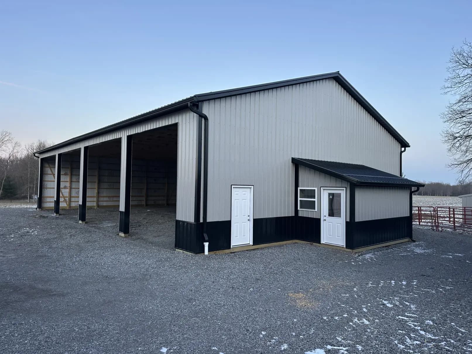 Gray steel pole barn with new black seamless gutters and downspouts