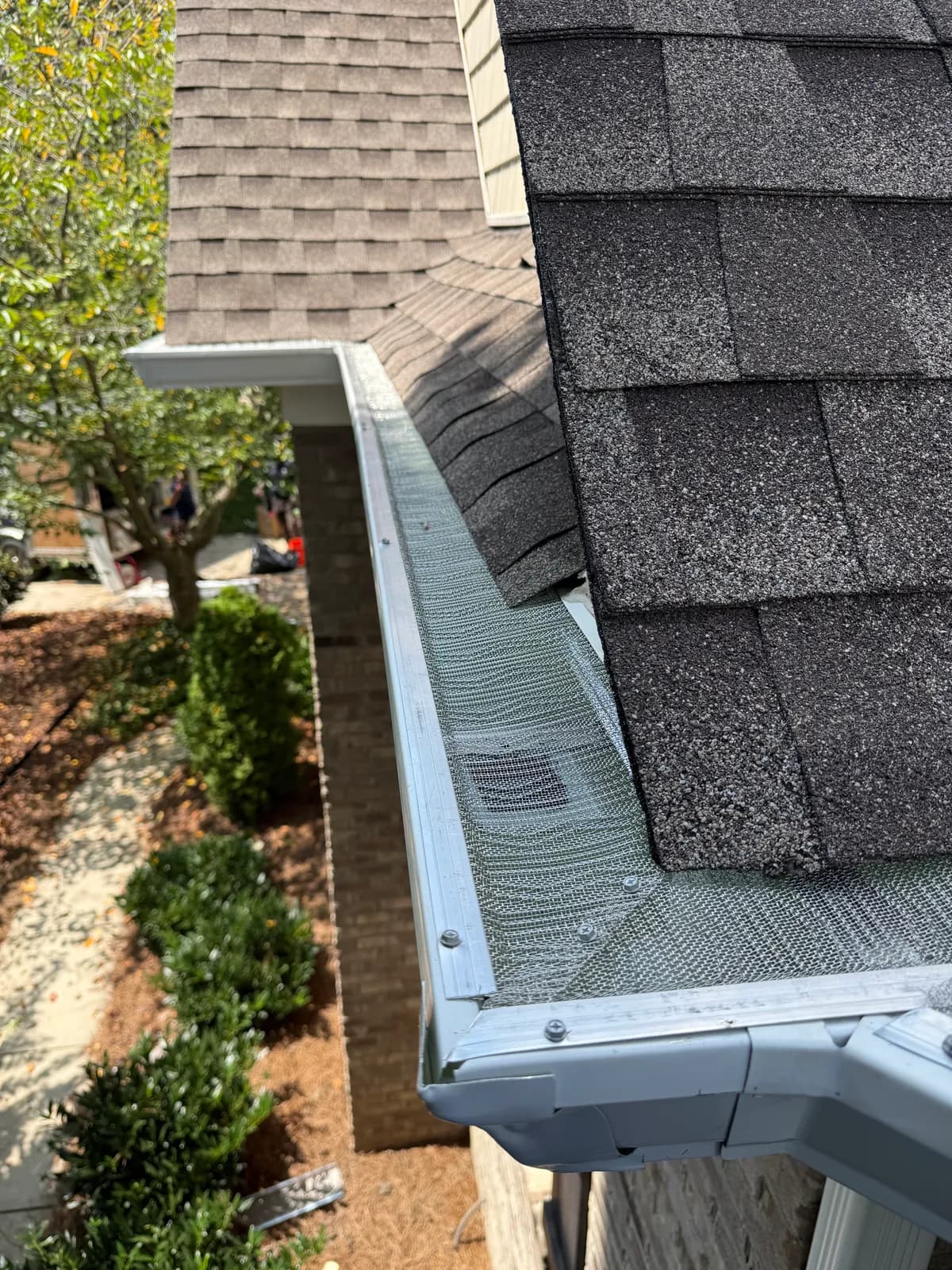 Stainless micro-mesh gutter guard wrapping an inside corner of a white gutter on a brick home in the Charlotte, NC area