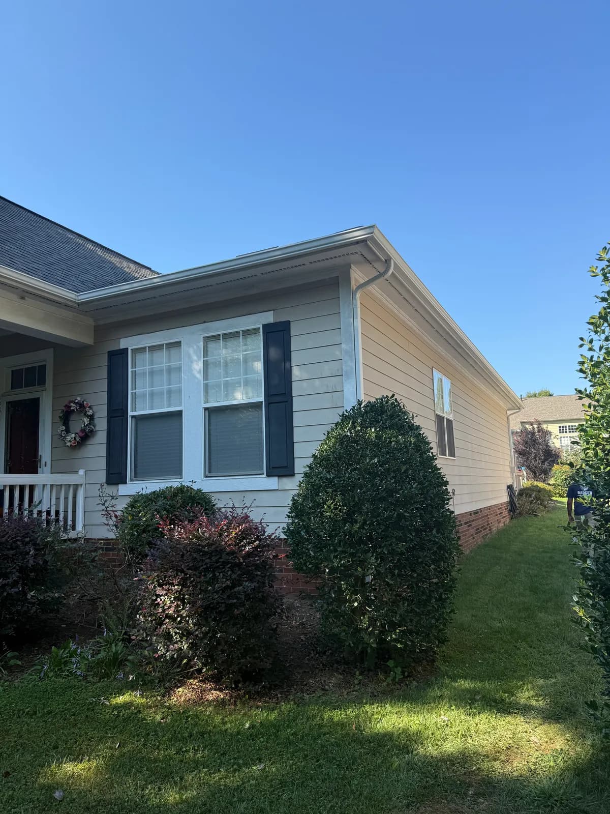 Side of a craftsman-style house with a white gutter and downspout and black shutters in the Charlotte, NC area