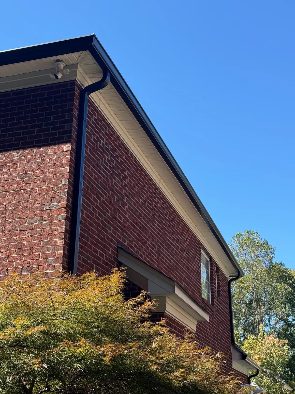 Black seamless gutters and downspouts on a red brick two-story home in the Charlotte, NC area
